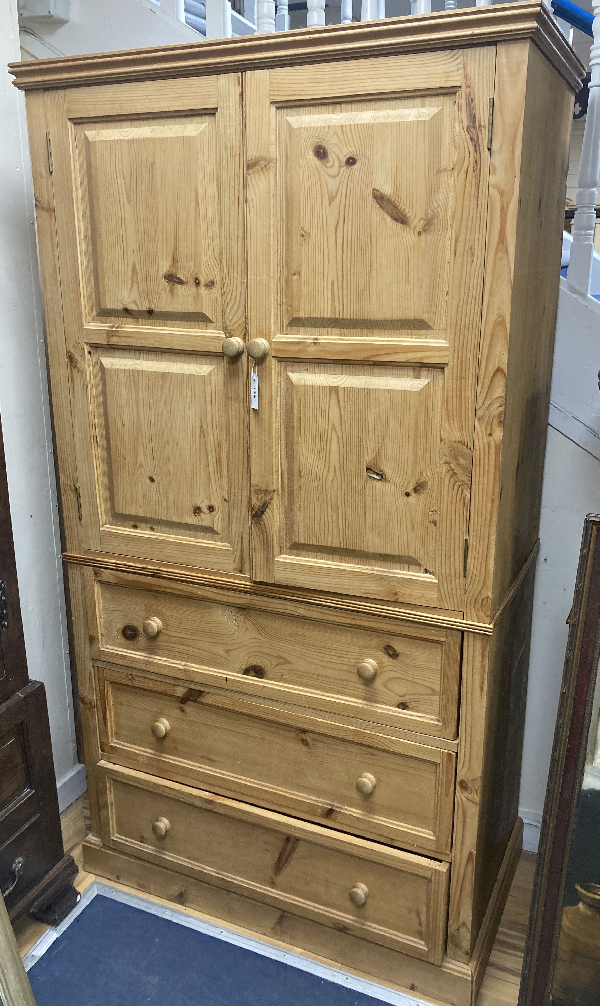 A contemporary pale pine press cupboard with twin panelled cupboard doors over a base fitted with three long drawers, height 199cm, wid